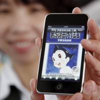 A woman in Beijing shows a mobile phone displaying an image of “Astro Boy,” a manga character created by Japan’s Osamu Tezuka, on April 7, 2010. Astro Boy manga sketches fetch record price at Paris auction