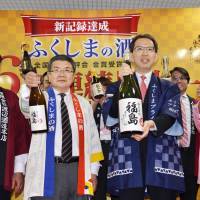 Officials and brewers from Fukushima Prefecture, including Fukushima Gov. Masao Uchibori (second from right), hold bottles of sake during a photo session Thursday at the prefectural government building in Fukushima City. Fukushima sake brands won the largest number of prizes at the Annual Japan Sake Awards. Fukushima tops national sake competition for record-setting sixth year