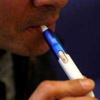 A man uses an iQOS e-cigarette. Phillip Morris' iQOS e-cigarette is capable of harvesting smoker's data: ex-project manager