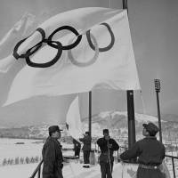 Members of Japan’s Ground Self-Defense Force are seen raising Olympic flags in Sapporo in a file photo taken Jan. 23, 1972, before the opening of the 1972 Winter Games. Sapporo Olympic bid chiefs remain vague over target year