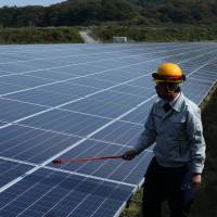 An engineer inspects solar panels in Awaji, Hyogo Prefecture. Japanese firms shift to clean energy despite state's enduring commitment to nuclear power
