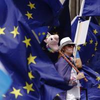 A pro-European Union and anti-Brexit demonstrator stands among European Union (EU) flags outside the Houses of Parliament in London on June 20. Brexit's big short: Hedge funds hired pollsters and cashed in