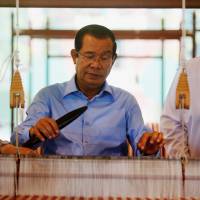 Cambodian Prime Minister Hun Sen weaves a krama cotton scarf during an attempt to break the world record for weaving the longest cotton scarf in Phnom Penh on June 7. U.S. sanctions Cambodian leader's top bodyguard over human rights abuses