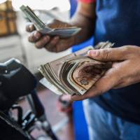 An Egyptian gas station worker counts cash in Cairo. Egypt increases fuel prices as part of austerity measures