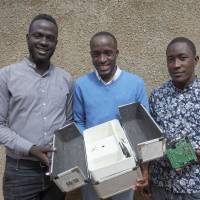 Brian Gitta (left), and team members Moris Atwine (center) and Shafik Sekito show off the non-invasive malaria test that Gitta invented in Kampala on June 18. Ugandan computer scientist wins prestigious engineering prize for developing non-invasive malaria test kit