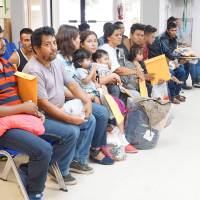 Edilberto Garcia, (second from the left), who was separated from his 17-year-old son after traveling from Honduras, sits among other migrants on Saturday soon after arriving at a humanitarian center in the border town of McAllen, Texas. U.S. Republicans fear conservative backlash over 'mass amnesty' for young immigrants