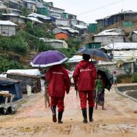 Save the Children representatives walk after a storm at the Chakmarkul refugee camp in Cox’s Bazar, Bangladesh, on June 10. Hiding from traffickers in 'prison-like' tents, Rohingya girls dream of school