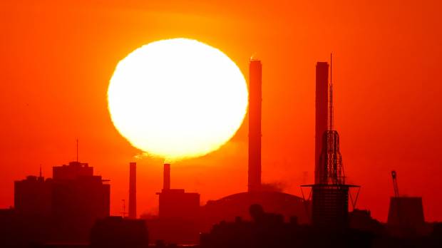 The sun rises behind chimneys of a power plant in Moscow in May. Over 200 million people in cities across the globe face stifling heat within the next three decades, researchers have warned. Cities face dramatically higher heat and flood risks by 2050, researchers say