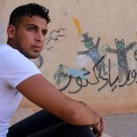 Moawiya Sayasina sits beside schoolyard graffiti reading, “Your turn, doctor” in a rebel-held neighborhood of the southern Syrian city of Daraa on June 5. Pair whose teen graffiti lit Syrian war brace for regime attack on hometown