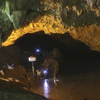 Rescuers talk each other on Saturday during a search operation at the entrance to a cave complex where 12 soccer team members and their coach went missing in Mae Sai, Chiang Rai province, in northern Thailand. Divers progress in cave search for missing Thai kids as international teams pitch in