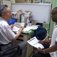 Yoneyuki Kobayashi, head of Kobayashi International Clinic in Yamato, Kanagawa Prefecture, treats Zimbabwean Andile Maqhuzu at the clinic on June 5. Medical institutions offering treatment in multiple languages make Japan a haven for foreign patients