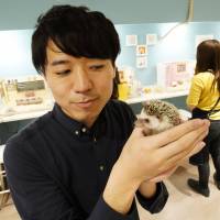 Masaki Shimizu, owner of a hedgehog cafe who also works at the IT firm En Factory, poses with a hedgehog at his ChikuChiku cafe in Tokyo on April 26. Second jobs, once rare in Japan, are reshaping attitudes about work
