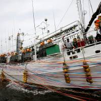 A crew member of the squid ship Hosei-Maru No. 58 waves to relatives as the ship leaves for a fishing run from Sakata, Yamagata Prefecture, on June 6. As squid season peaks, Japanese fishermen fear confrontation with North Korean boats