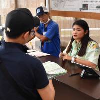 Staff at a Luft Travel Rent-a-Car outlet in Okinawa Prefecture speak to foreign tourists on May 18. Okinawa car rental agencies wary of Chinese tourists with improperly obtained licenses