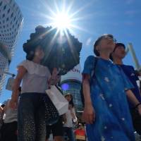 People cross a street in Tokyo’s Ginza shopping district on Friday. The Japan Meteorological Agency announced on Friday that the rainy season has ended in the Kanto-Koshin region, including the Tokyo area. Tokyo area sees earliest end to rainy season on record