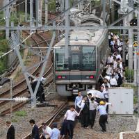 Stranded passengers walk along a railroad track following an earthquake in Osaka on June 18. Struggling to stay on top of fake social media posts in a disaster