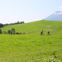 Mountain bikers cycle against a backdrop of Mount Yotei and beautiful nature. | NISEKO PROMOTION BOARD