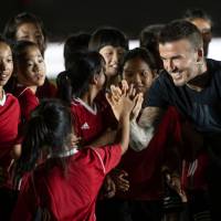 Former England captain David Beckham interacts with children during a promotional event on Wednesday for a sportswear company and a collegiate soccer association in Beijing. David Beckham predicts an England-Argentina final at World Cup