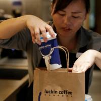 A barista packs a coffee for online orders at a Luckin Coffee store in Beijing on July 17. China's caffeine war: Fast-growing Luckin brews up a threat to Starbucks