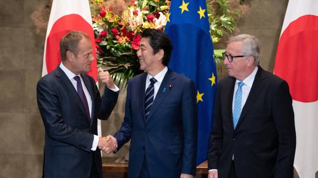 Prime Minister Shinzo Abe shakes hands with European Council President Donald Tusk as European Commission President Jean-Claude Juncker looks on before signing a free trade pact in Tokyo on Tuesday. Japan and the European Union complete trade deal accounting for 30 percent of world's GDP