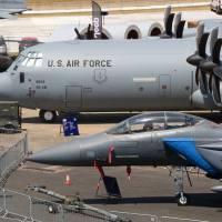 Attendees take selfie photographs with an F-15E Strike Eagle fighter jet, produced by Boeing Co., during preparations ahead of the Farnborough International Airshow (FIA) 2018 in Farnborough, U.K., on Sunday. The air show, a biannual showcase for the aviation industry, runs until July 22. Plane makers plot course through trade, Brexit worries to air show deals
