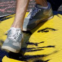 A man steps on a portrait of Russian President Vladimir Putin during a protest over the government’s decision to increase the retirement age, in Moscow Sunday. Protesters chant anti-Putin slogans at Moscow rally against plan to up retirement age