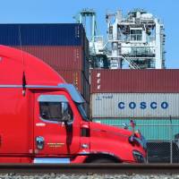 A delivery truck passes containers stacked at the Port of Long Beach in California, including one from COSCO, the Chinese state-owned shipping and logistics company. Tokyo expresses concern as U.S. announces fresh tariffs on China in escalating trade war
