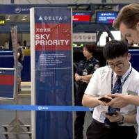 A staff member assists a passenger near the check-in counters for Delta Air Lines at Beijing Capital International Airport in Beijing July 6. China says there will be “no room for negotiation” as it demands U.S. airlines describe self-ruled Taiwan as part of China ahead of a Wednesday deadline. Delta Air Lines and American Airlines are among the last major carriers to refer to Taiwan as its own region or country. U.S. airlines to yield to Beijing's demands, will refer to 'China Taiwan'