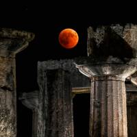 The full moon is seen during a “blood moon” eclipse over the temple of Apollo in Corinth on Friday. 'Blood Moon' dazzles stargazers in longest lunar eclipse of 21st century