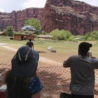 This Thursday photo released by Benji Xie shows a helicopter landing to rescue people from flooding on the Havasupai reservation in Supai, Arizona. Rescue workers were evacuating about 200 tourists Thursday who were caught in flash flooding at a popular campground on tribal land near the Grand Canyon where visitors go to see towering blue-green waterfalls. Flash floods force 200 tourists to flee to high ground at Grand Canyon waterfalls