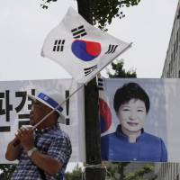 A supporter of former South Korean President Park Geun-hye waves a national flag near the Seoul Central District Court on Friday. South Korea's ex-President Park given eight more years in prison