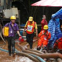 Rescue workers come out from the Tham Luang cave complex, as members of under-16 soccer team and their coach have been found alive according to a local media’s report, in the northern province of Chiang Rai, Thailand, Tuesday. Warm in blankets, Thai boys smile and joke with rescuer in cave