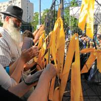 People hang yellow ribbons with Jewish names during Remembrance March, organized to commemorate the 76th anniversary of the first deportation from the Warsaw Ghetto in Warsaw Sunday. March honors Warsaw's Jews and escapee activist who warned of genocide