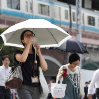 A woman sips water in front of JR Shinbashi Station in Tokyo on Monday as a record high temperature of 40.8 degrees was set in the capital. Heat wave sends mercury to all-time high of 41.1 in Saitama