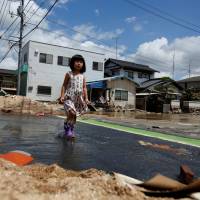 A girl walks through Mabicho district in Kurashiki, Okayama Prefecture, on Tuesday. In flood-hit area of Okayama, residents shocked by scale of destruction
