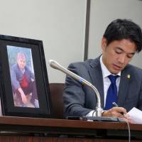 A photo of Arjun Bahadur Singh, a Nepalese man who died last year while being interrogated by prosecutors, is displayed at a news conference Friday in Tokyo next to lawyer Yoshihito Kawakami. Wife of Nepalese man who died during interrogation sues state, Tokyo Metropolitan Government