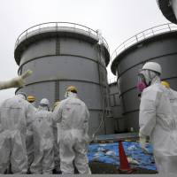 Journalists wearing protective suits view tanks containing radioactive water during a media tour of the Fukushima No. 1 nuclear power plant in August 2013. At least four firms used foreign trainees to clean up radioactive contamination from Fukushima nuclear plant: ministry