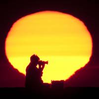 Perfect shot: A photographer composes a sunrise photo in Saco, Maine. Professional vacation photographer services are becoming more popular with tourists who doubt their creative skills. Better holiday pics, without using a selfie stick