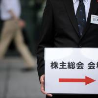 An attendant holds a sign for a shareholder meeting in Tokyo in June 2015. Shareholder meetings: What's your version?