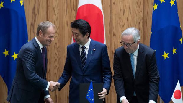Prime Minister Shinzo Abe shakes hands with European Council President Donald Tusk as European Commission President Jean-Claude Juncker looks on after the signing of a Japan-EU trade deal in Tokyo on Tuesday. Japan stands beside Europe on free trade