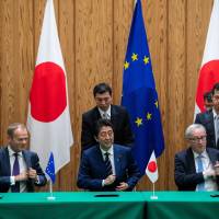 Prime Minister Shinzo Abe, European Council President Donald Tusk (left) and European Commission President Jean-Claude Juncker reach for their pens at a July 17 signing ceremony for a trade deal that will eliminate almost all tariffs between Japan and the EU. Japan is going global as America looks inward