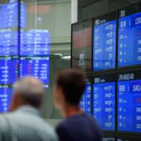 Visitors look at screens displaying stock indices at the Tokyo Stock Exchange in July. BOJ's tolerance of bigger stock drops shows 'stealth tapering' underway: analysts