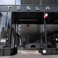 A woman walks past a Tesla showroom in Washington on Aug. 8. Tesla CEO Elon Musk disclosed on Monday he was in talks with Saudi Arabia’s sovereign wealth fund and other investors to take the electric automaker private. Tesla's slow disclosure after Musk's tweet of going private raises governance concerns