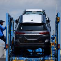 A worker prepares to unload Toyotas from a car carrier at Nagoya Port on July 31. Japan fell into red ink in goods trade for the first time in two months in July as the cost of energy imports surged. Japan logged ¥231 billion trade deficit in July as oil prices climbed