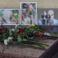 A picture taken Wednesday shows flowers left in front of the photographs of Russian journalists (from left) Alexander Rastorguyev, Kirill Radchenko and Orkhan Dzhemal, who were recently killed in the Central African Republic, outside the Central House of Journalists. Kremlin critic vows to find killers of TV crew in Central African Republic reporting on Russian mercenaries