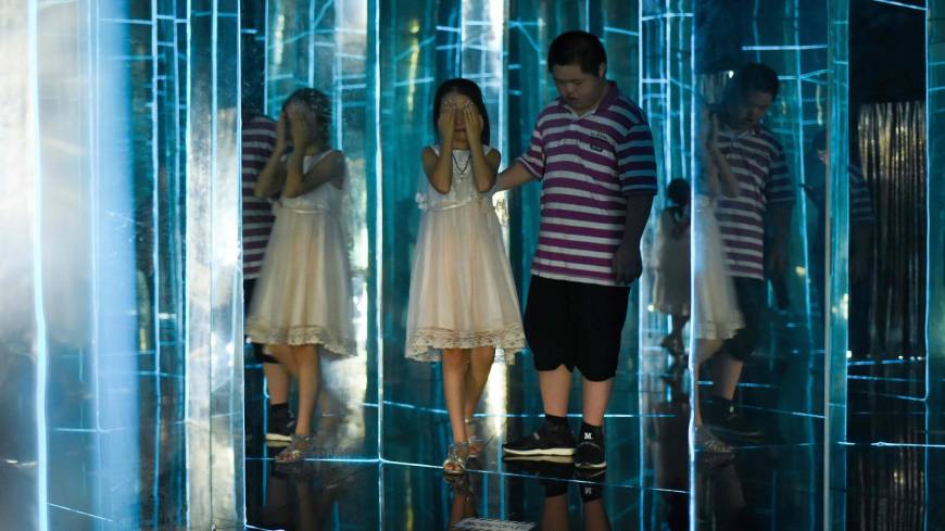 Children visit a maze constructed with mirrors at a mall in Beijing on Thursday. No children? Pay a tax, Chinese academics suggest