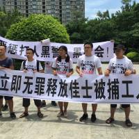 People hold banners at a demonstration in support of factory workers of Jasic Technology, outside Yanziling police station in Shenzhen on Aug. 6. China's student activists cast rare light on brewing labor unrest