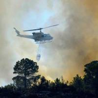 A helicopter drops water over a wildfire in Pinet, in the eastern Spanish region of Valencia, on Tuesday. In the Valencia region some 2,500 people were driven from their homes overnight to escape flames that have already swept across around 1,000 hectares, as fire crews struggled to bring the fires under control. New normal: Dry and on fire from Mediterranean to Arctic, Europe battles deadly heat