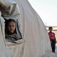 A young boy peeks out of a tent in a camp for the displaced from Idlib’s southern province and Hama’s northern provice, in Kafr Dariyan situated a short distance from Syria’s border with Turkey, on Sunday. U.N. concerns mount over civilians in Syria's rebel-controlled Idlib ahead of looming regime onslaught