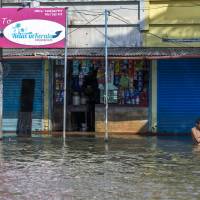 A man bathes in floodwater in front of a grocery store and other shuttered businesses in Kainakary village in the district of Alappuzha, Kerala, in India, on Aug. 22. South Asia monsoon rains that killed 1,200 and displaced a million match climate change forecasts: scientists